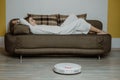Robotic Vacuums, Robot Mops. Smart home. Robotic Vacuum Cleaner while Woman Relaxing on sofa. Automatic robotic vacuum Royalty Free Stock Photo