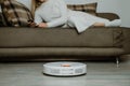 Robotic Vacuums, Robot Mops. Smart home. Robotic Vacuum Cleaner while Woman Relaxing on sofa. Automatic robotic vacuum Royalty Free Stock Photo