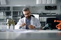 Robotics engineer working on desing of modern robotic arm and sitting at desk in laboratory.