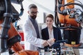 Robotics engineers with tablet dicussing and desinging modern robotic arm in factory. Royalty Free Stock Photo