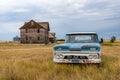 Robsart, SK- August 21, 2021:  A blue and white classic pick up truck and abandoned home in Robsart, SK Royalty Free Stock Photo