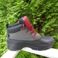 Robust, waterproof outdoor boot for men, side view, in front of a green hedge