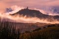 Rocca di Radicofani main tower fortification covered with morning mist. Sunrise light covering the curly clouds running over Royalty Free Stock Photo