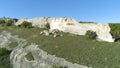 Rock above gorge. Shot. Top view of landscape of stone ridge hills, blue sky and green gorge. Sunny day in mountain