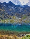 A rock above the lake. A large dry river bed and river of melted snow, a snow-covered mountain. Blue water waterfalls. Emerald Royalty Free Stock Photo