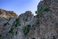 Rock with ancient walls of Alanya Castle Turkey on top - bottom view. A steep cliff with green plants on a stone slope against a Royalty Free Stock Photo