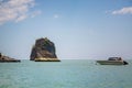 The rock in the andaman sea is painted with gold paint. Thai spirituality. Speedboat floats nearby. Blue sky, a lot of clouds.