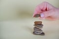 Rock balancing. A female hand on a yellow background lays small sea stones on top of each other. Balanced Stone or Balancing Rock Royalty Free Stock Photo