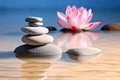 Rock balancing. Small zen stacking stones piled in balanced in water with pink lotus flower Royalty Free Stock Photo