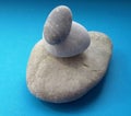 Stone balance with three different sized stones over blue background. Pebbles stack.