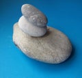 Stone balance with three different sized stones over blue background. Pebbles stack.