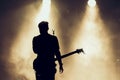 Rock band performs on stage. Guitarist plays solo. silhouette of guitar player in action on stage in front of concert crowd. Close Royalty Free Stock Photo