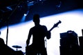 Rock band performs on stage. Guitarist plays solo. silhouette of guitar player in action on stage in front of concert crowd. Close