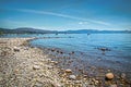 Rock beach at Lake Tahoe California with moored boats and dock and mountains in background