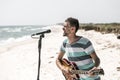 Rock on the beach, the musician plays the guitar and sings into the microphone, the concept of leisure and creativity