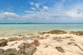 Rock beach with white sand and cloudy blue sky Royalty Free Stock Photo