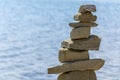 Rock cairn the art of stone balancing on a stone near a blue water flowing lake.