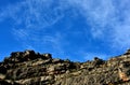 Rock cliff against blue sky with clouds and a day moon Royalty Free Stock Photo