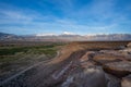 Rock cliff elevated view of river valley and dirt road below and snowy mountains