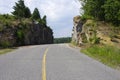 Rock cliff wall beside smooth paved road with yellow solid line Royalty Free Stock Photo
