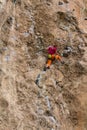 Rock climber girl in orange pants leaging climbing route on natural rock