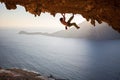 Rock climber climbing along roof in cave at sunset Royalty Free Stock Photo