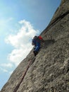 Rock climber dressed in bright colors on a steep granite climbing route in the Alps