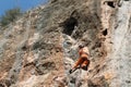 Rock climber girl leaging climbing route on natural rock