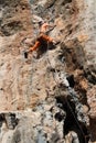 Rock climber girl in orange pants leaging climbing route on natural rock