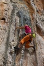 Rock climber girl in orange pants leaging climbing route on natural rock Royalty Free Stock Photo