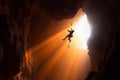 rock climber hangs on a rope in a deep abyss, the sunlight filtering through the rocks as they display their strength