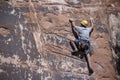 Rock climber man free climbing solo up handholds and footholds on red sandstone cliffs to set pitons and ropes in Moab, Utah