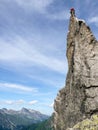 Rock climber sitting atop a sharp rock needle in the Val Bregaglia