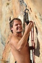 Rock climber struggling to fasten rope to quick-dr