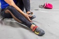 Rock climber woman sitting on a bouldering climbing wall holl, inside on colored hooks