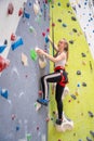 Rock climber young woman hanging on colored hooks on climbing artificial wall indoors of sport centre of Prague. Extreme Royalty Free Stock Photo