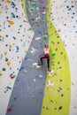 Rock climber young woman hanging on colored hooks on climbing artificial wall indoors of sport centre of Prague. Extreme Royalty Free Stock Photo