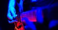 Rock concert. Guitarist plays the guitar. The guitar illuminated with bright neon lights. Hand close up