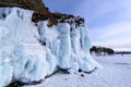 Rock covered with icicles. Lake Baikal in cloudy weather.