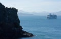 A rock in the foreground, in the background a large cruise ship leaving the Otago Peninsula near Dunedin in New Zealand Royalty Free Stock Photo