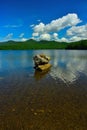 Rock formation in the middle of the clear lake with a reflection of the sky in the water Royalty Free Stock Photo