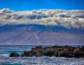 Rock formation at the ocean shore touching the fluffy cloudy sky