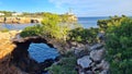 Rock formations including a natural hole and a lighthouse in the backdrop, mallorca Royalty Free Stock Photo