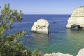 Rock formations and people doing kayaks in the Atlantic ocean to visit the Benagil caves seen from above, Algarve, Portugal