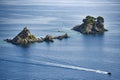 Rock islands on the sea off the coast of Croatia with a motorboat sailing along.