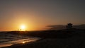 A rock jetty reaches into the ocean at sunset, with lifeguard stand in silhouette Royalty Free Stock Photo