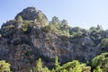 Rock mountain cliff with green grass and trees under blue sky Royalty Free Stock Photo