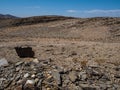 Rock mountain dried dusty landscape ground of Namib desert with splitting shale pieces, other stone, desert plant and blue sky