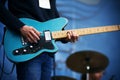 A rock musician plays on a blue six-string electric guitar