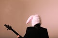 Rock musician wears bunny ears posing with electric guitar. Back view. Royalty Free Stock Photo